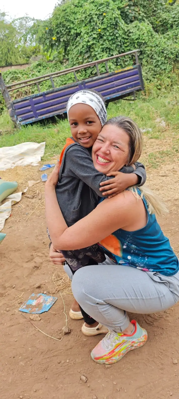 A woman crouching to hug a smiling child