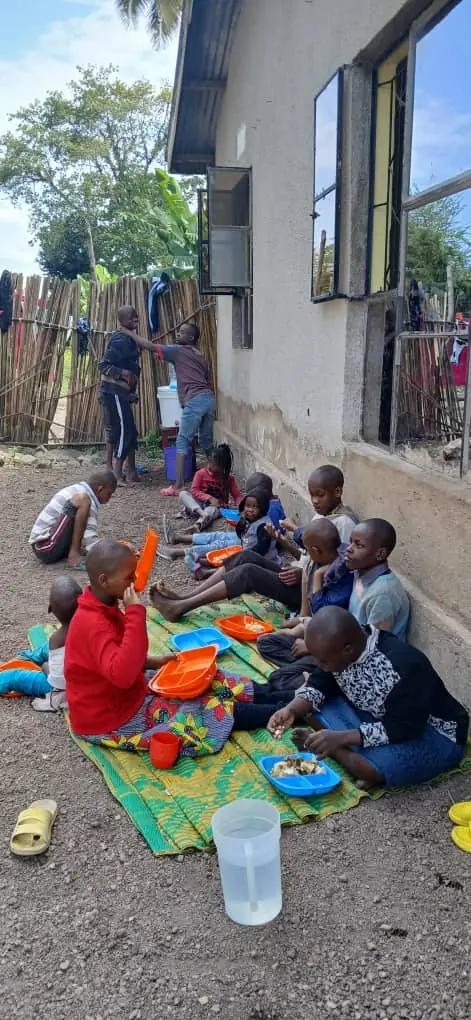 Children sharing a meal on mats outside a building