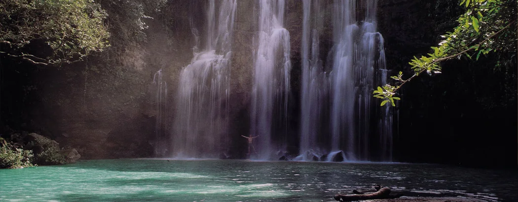 A waterfall falling into a green pool near Mto wa Mbu